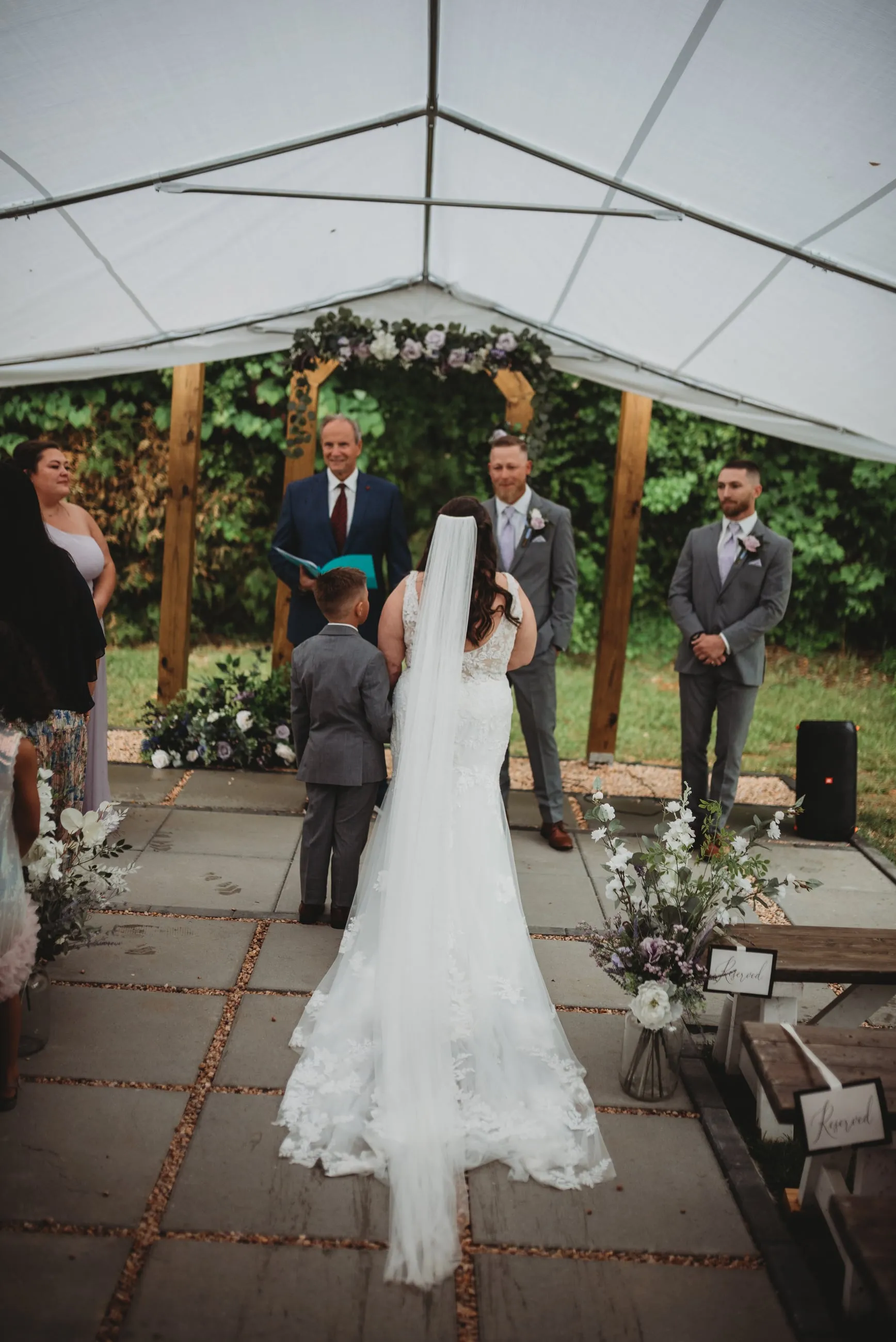 Bride standing with the wedding party during an outdoor ceremony at The Heritage Barn