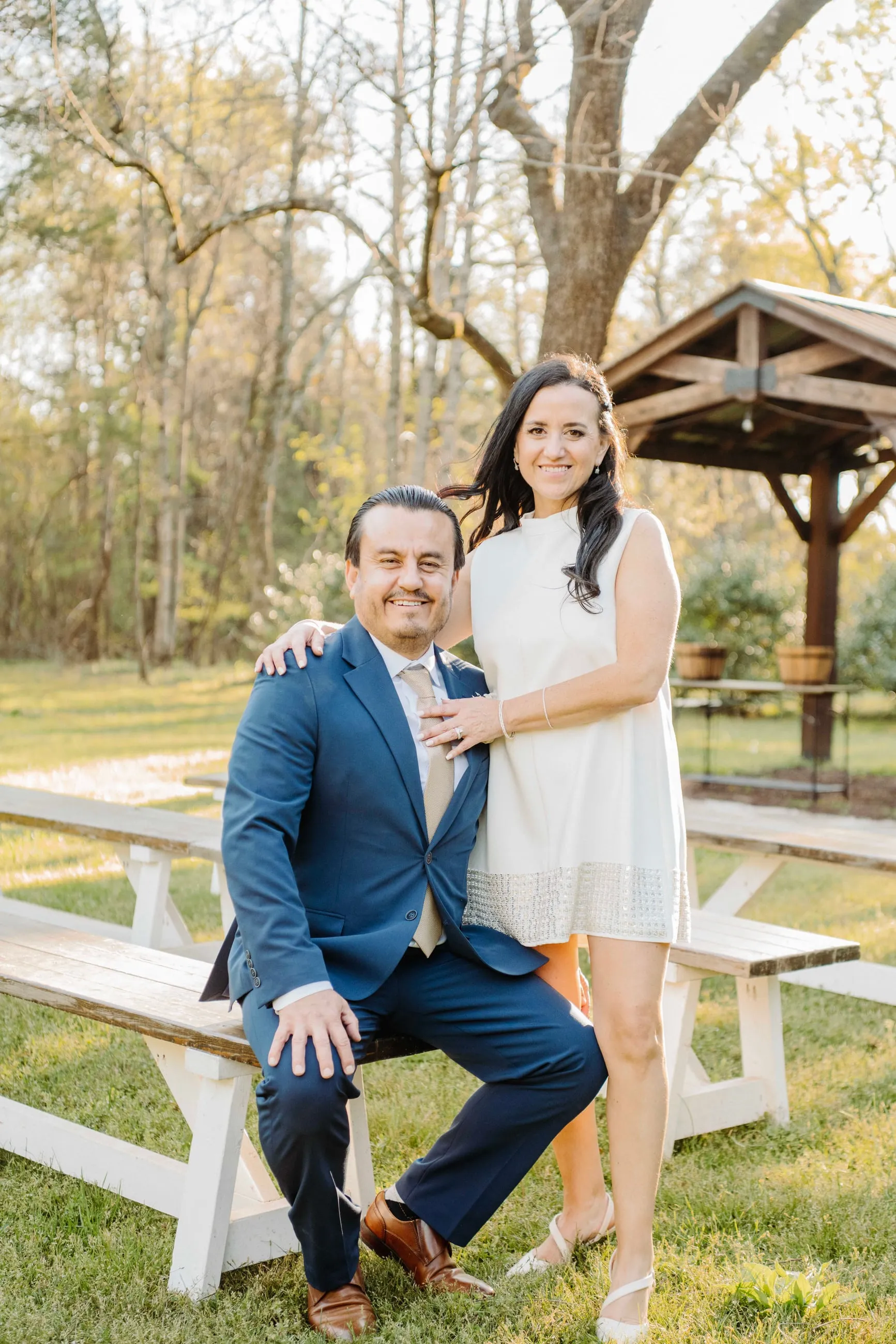 Couple posing for a bright outdoor portrait beside the pavilion at The Heritage Barn