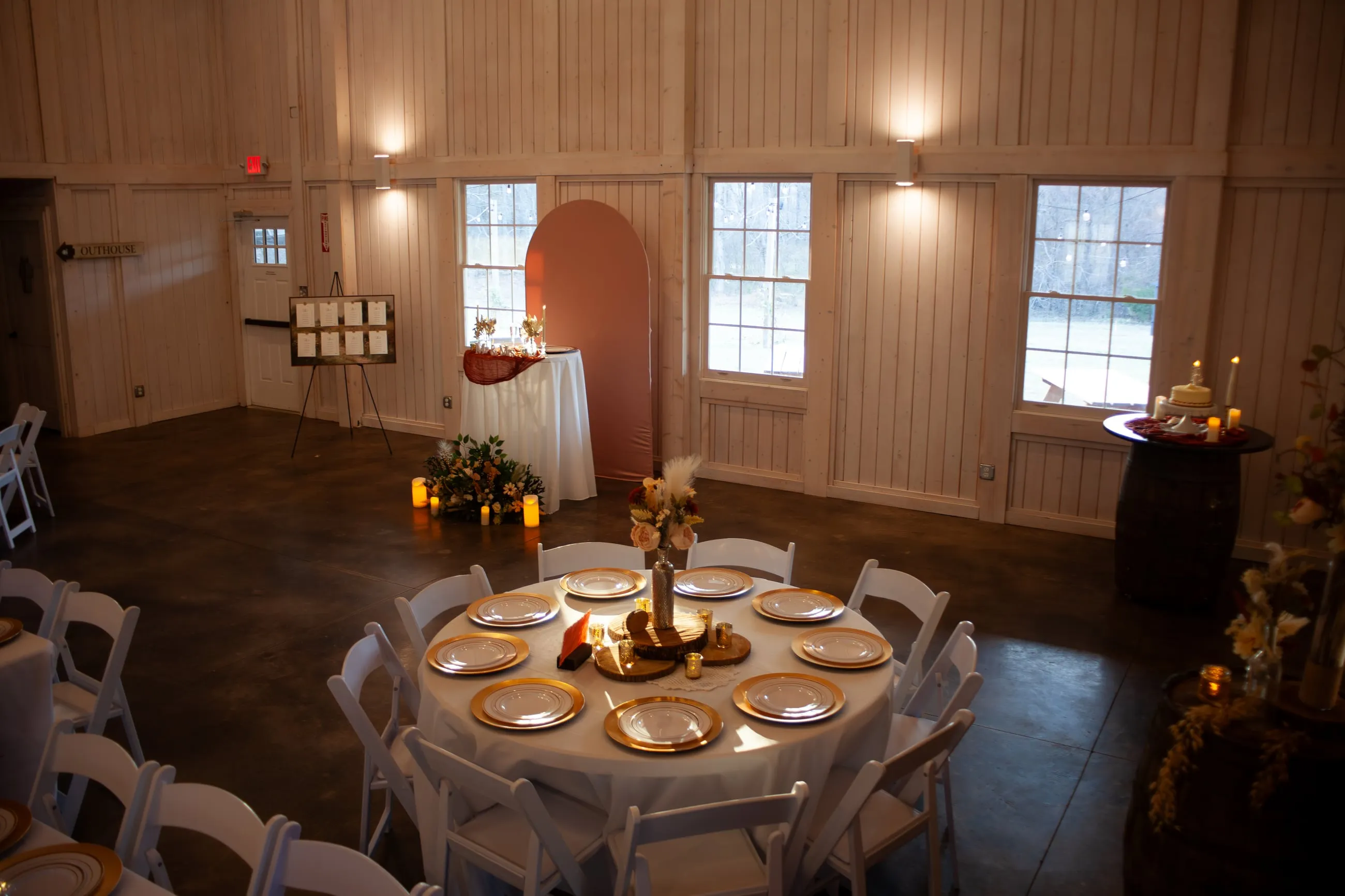 Elegant reception setup with long tables, candles, and florals inside The Heritage Barn