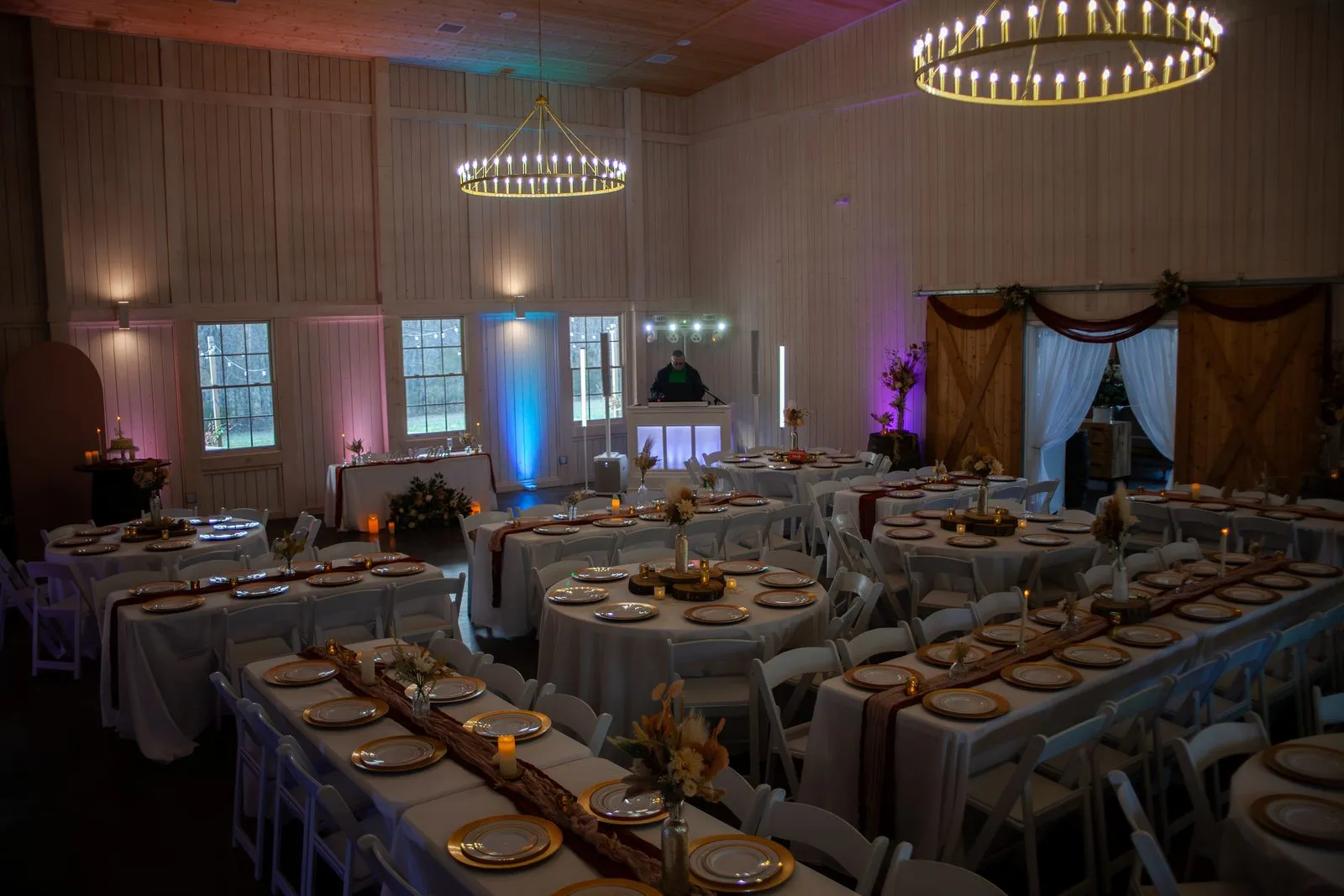 Reception tables glowing beneath chandeliers in the barn at The Heritage Barn, Conover NC